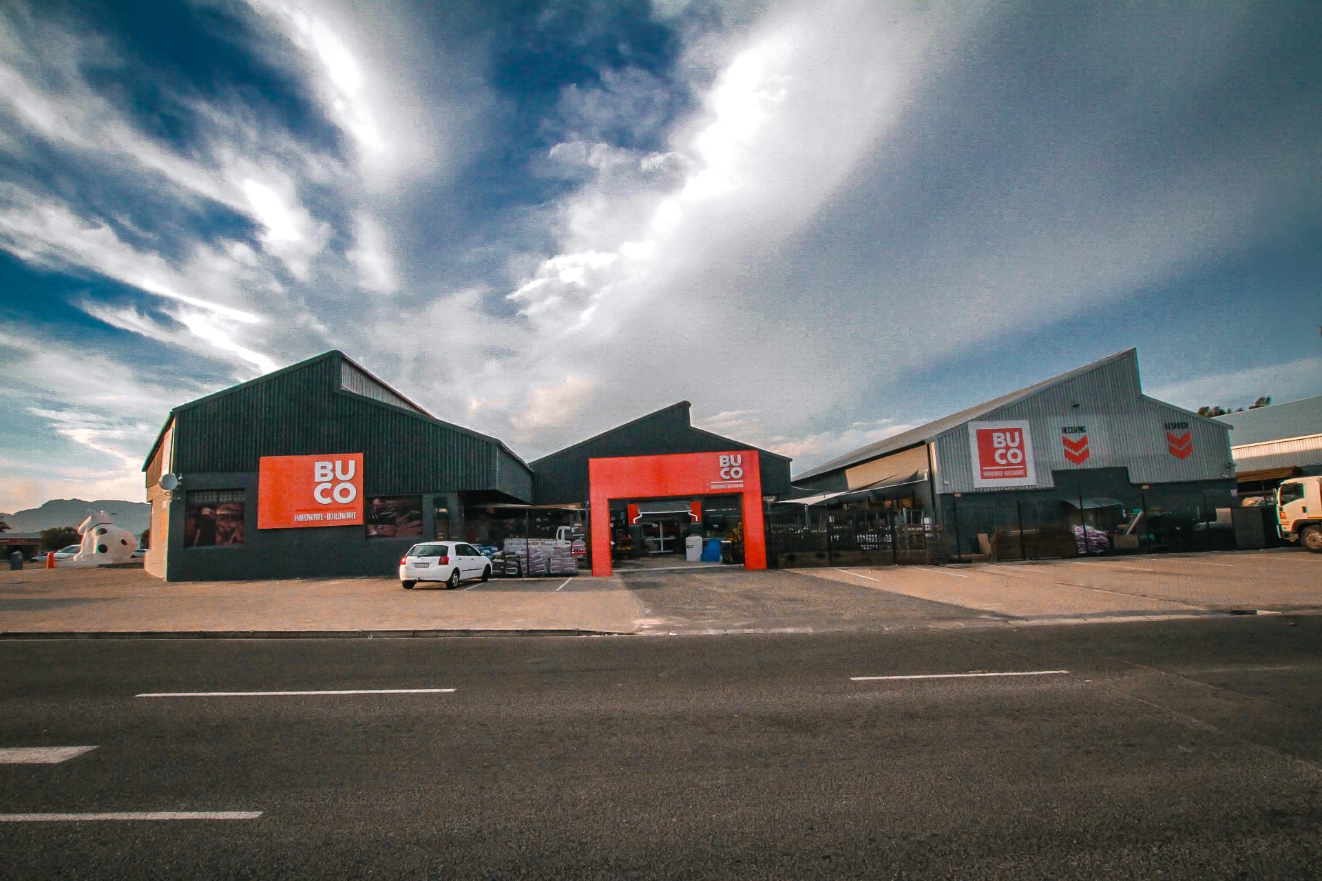 BUCO hardware store exterior in Tokai under dramatic clouds