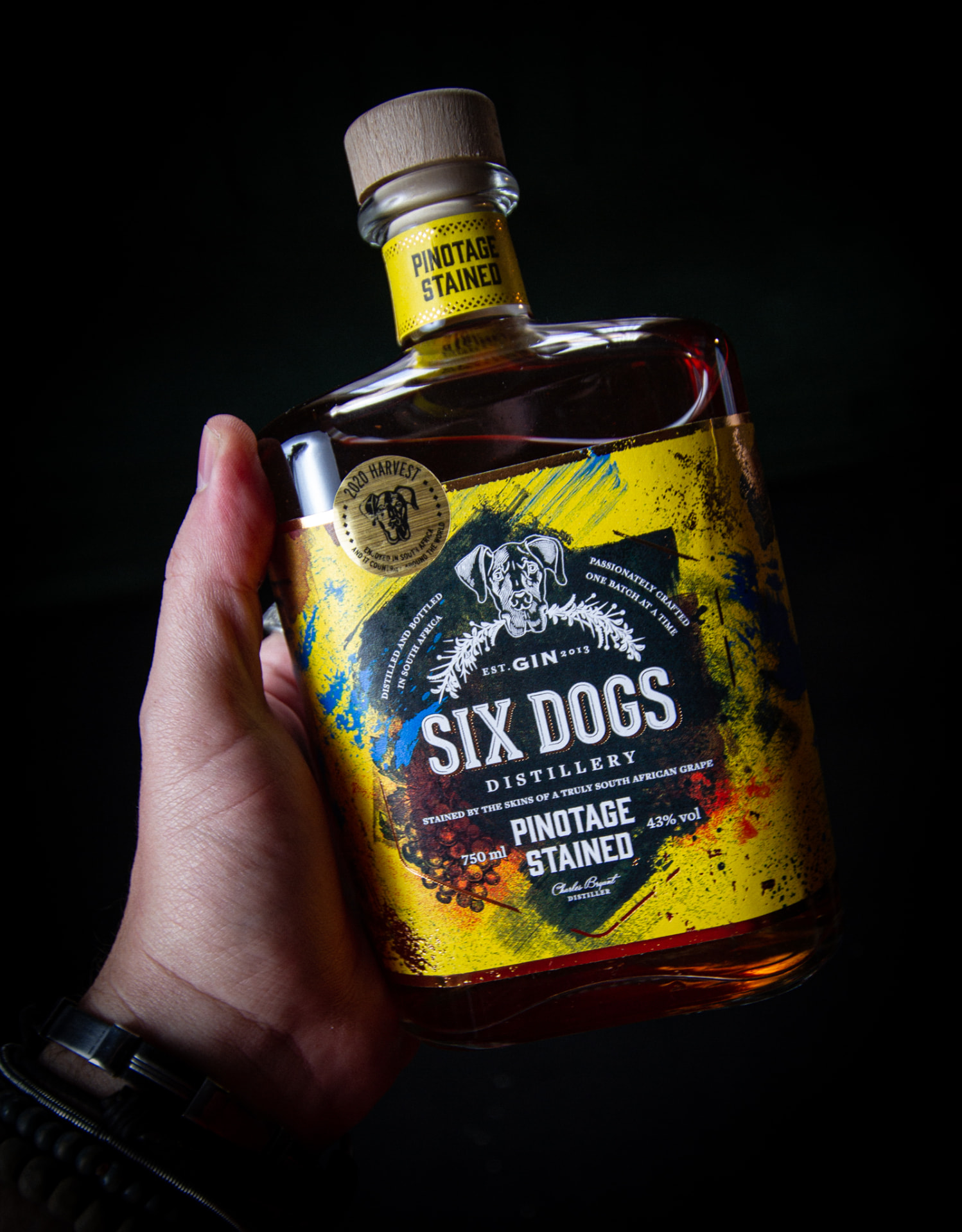 Product shot of a Six Dogs Pinotage Stained gin bottle held against a black background