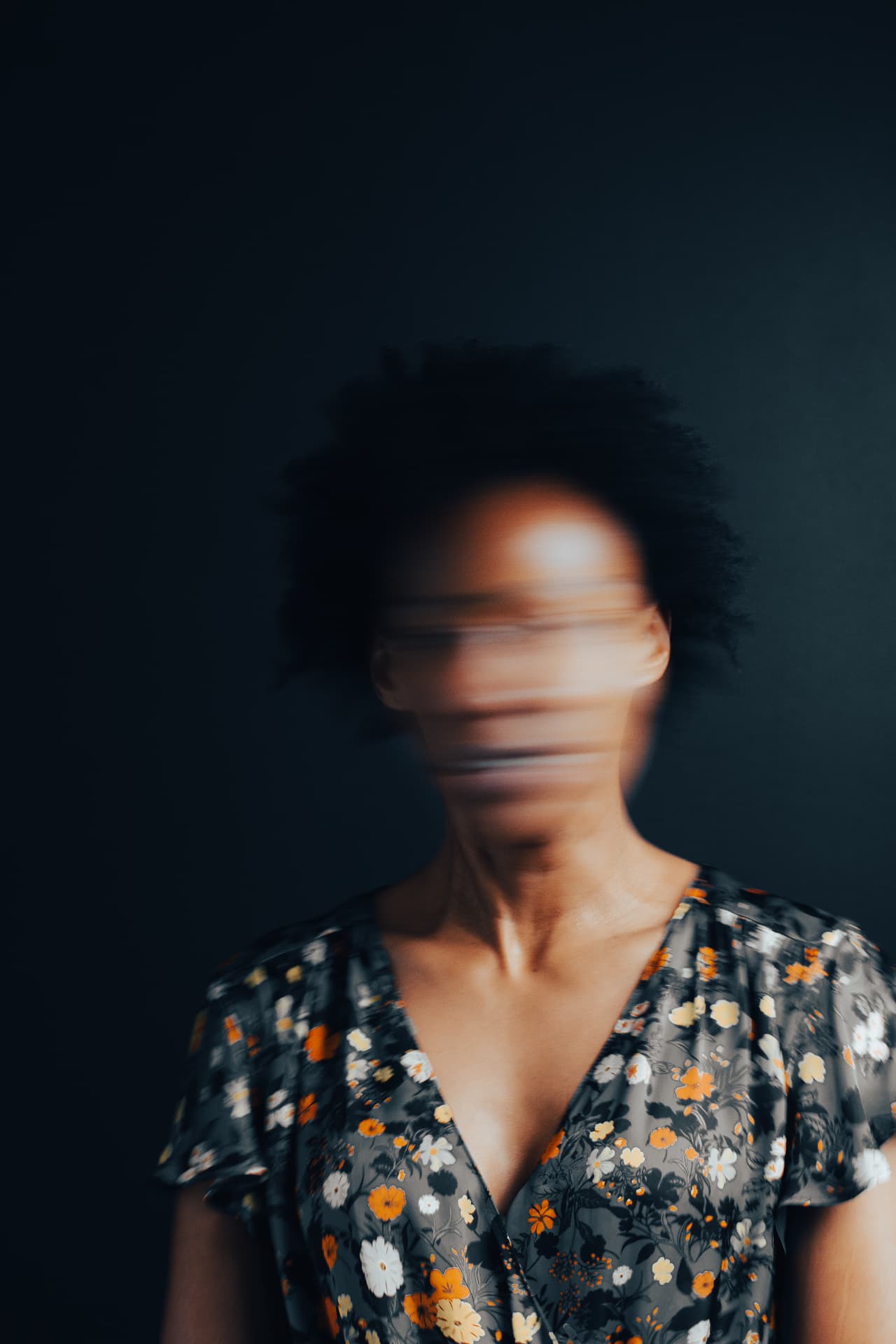 Motion blur portrait of a woman in a floral dress against a dark background