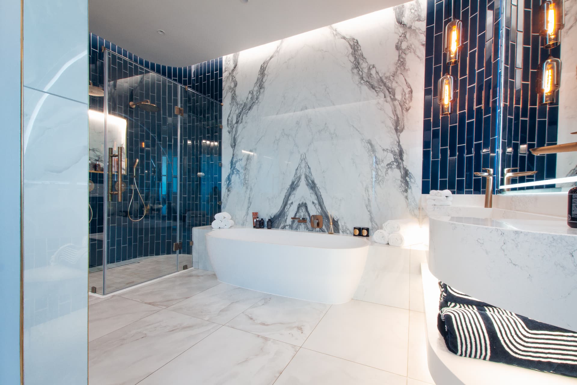 Ocean1 penthouse main bathroom with freestanding tub and marble wall