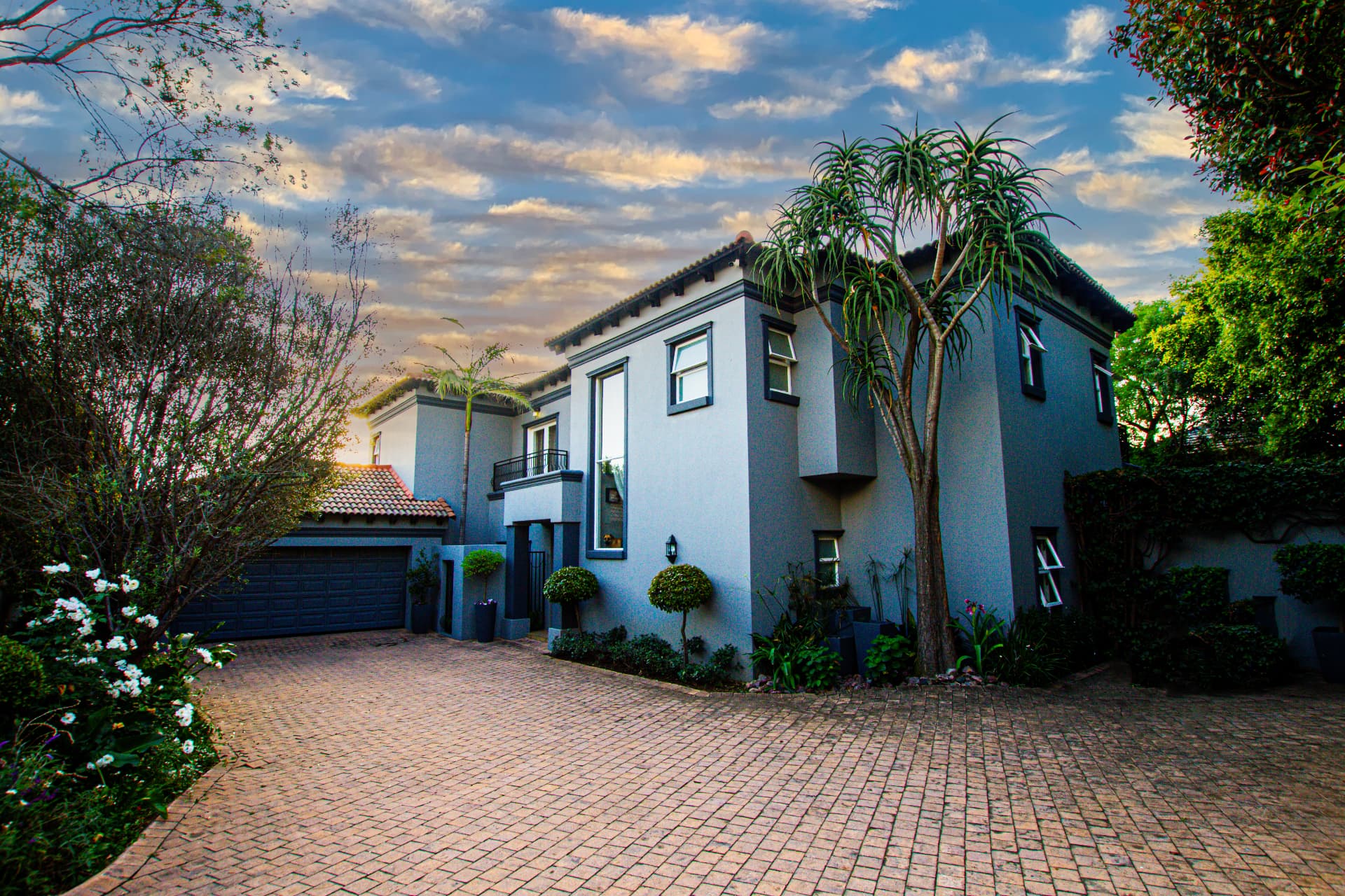 Mediterranean style Bryanston home exterior with driveway and landscaped garden at sunset