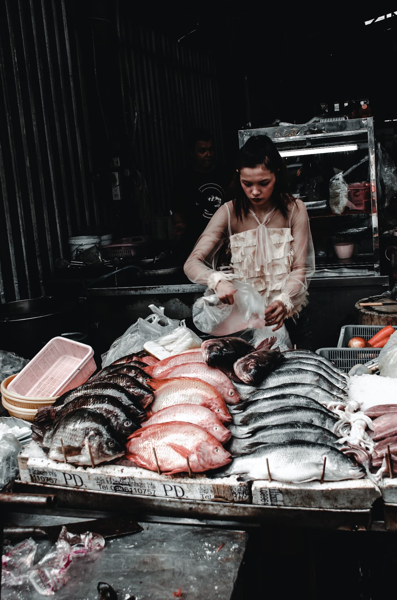 Street photograph of a vendor at a fresh fish market stall