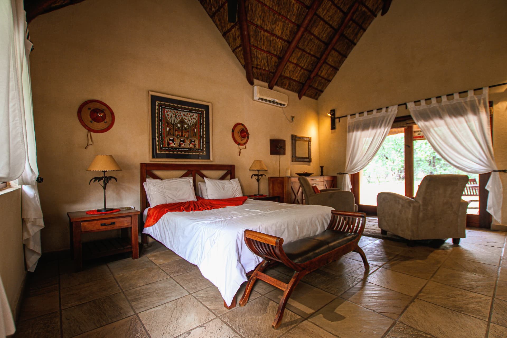 Luxury thatched lodge suite interior with four poster bed and private patio