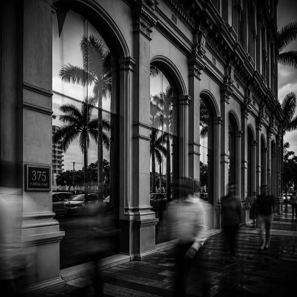 Moody black and white Durban colonial building with arched windows and blurred street activity