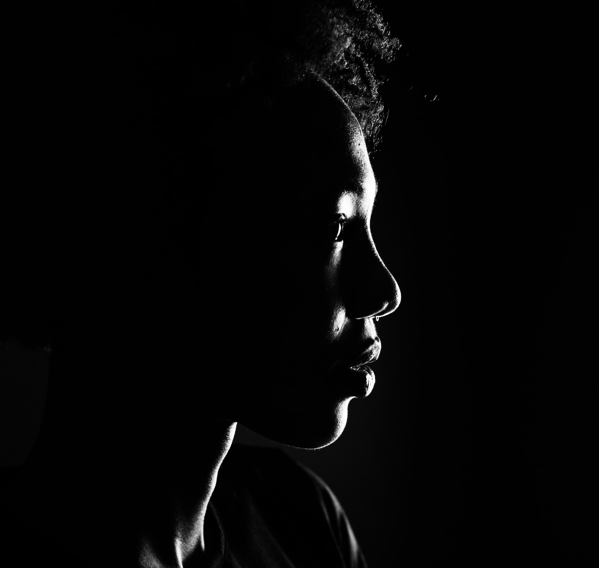 Dramatic black and white side profile portrait against a dark background