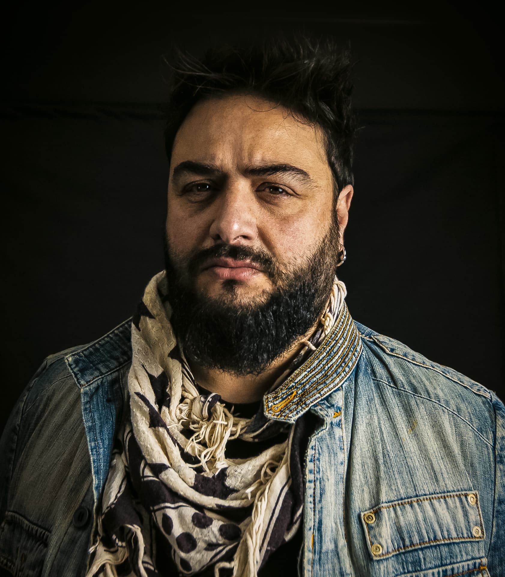 Low key portrait of a bearded man in a denim jacket and scarf