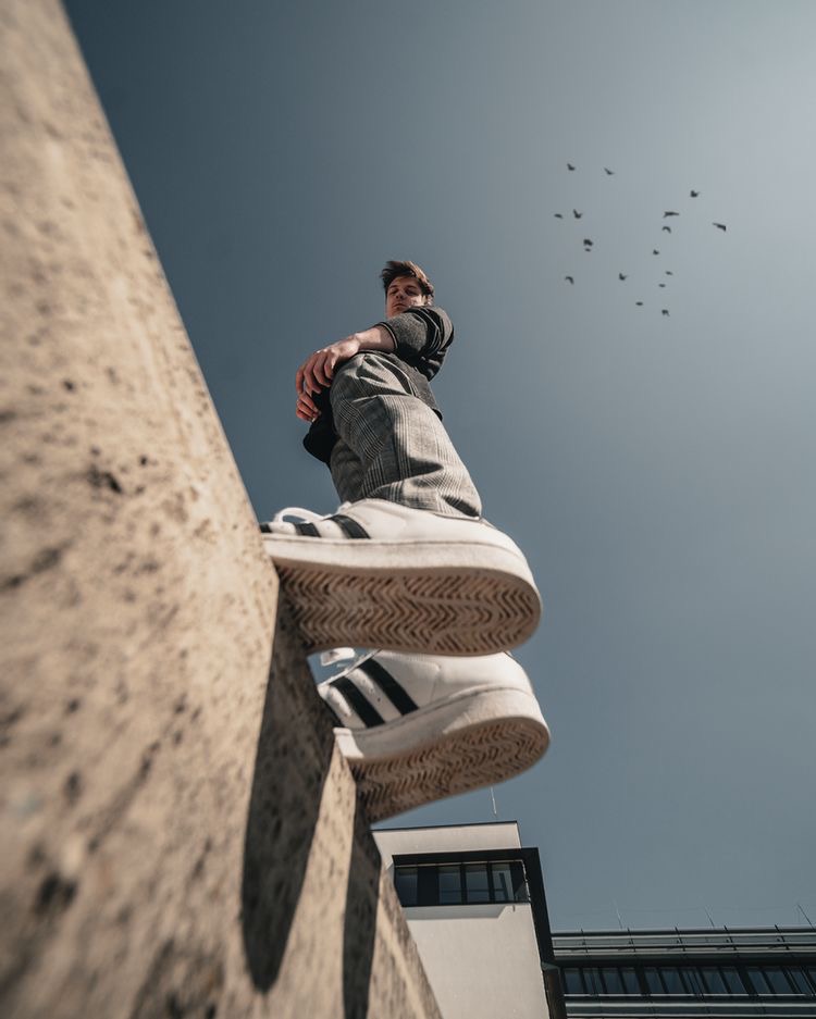 Low angle shot of a skater sitting on a concrete ledge against the sky