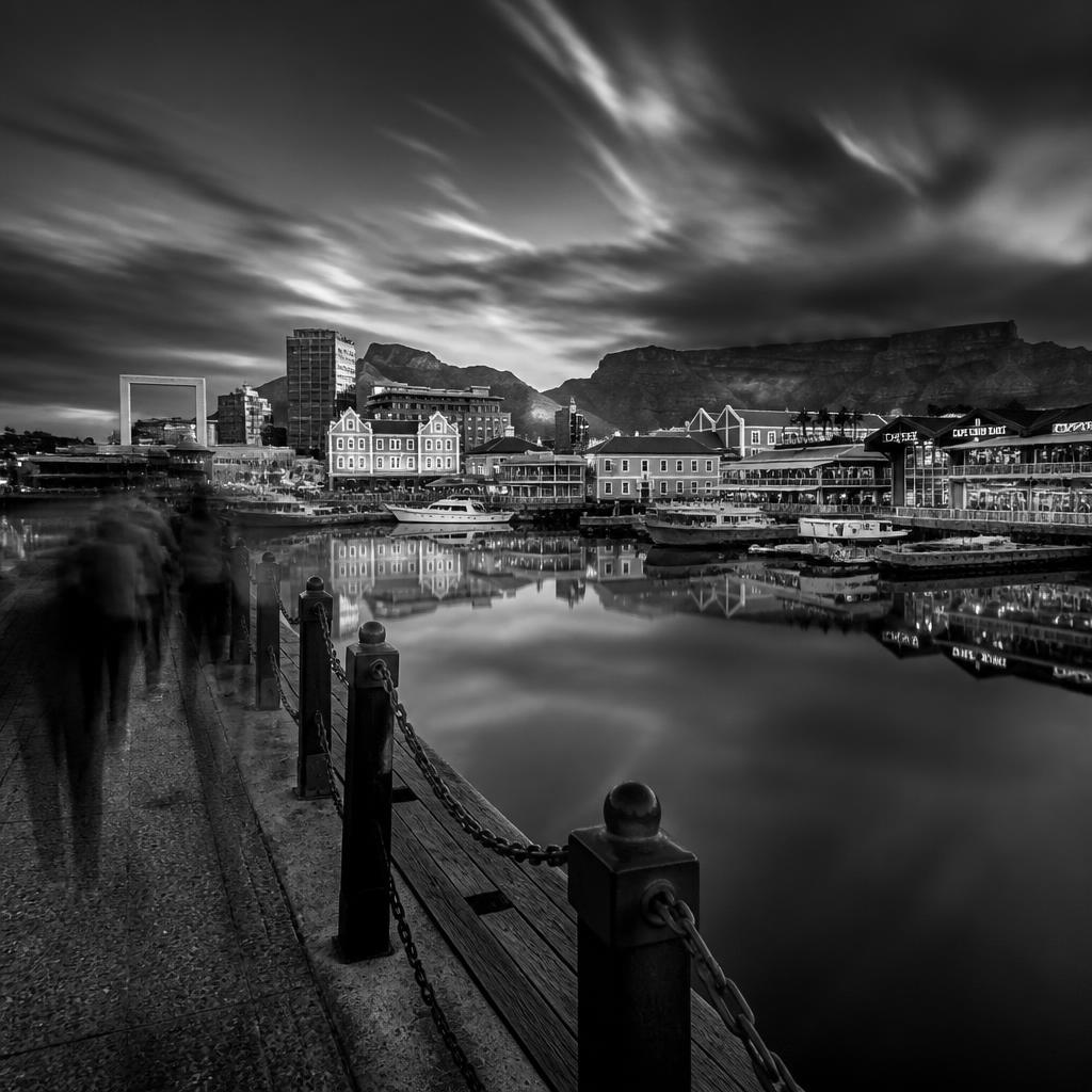Moody black and white Cape Town V&A Waterfront reflections with blurred figures walking