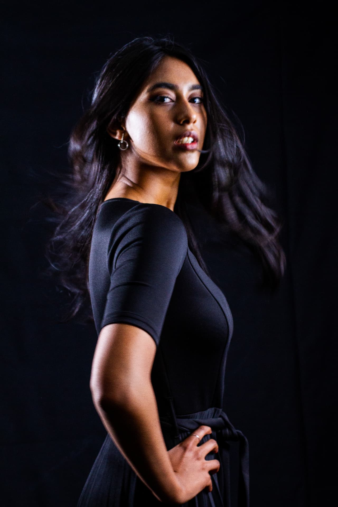 Studio fashion portrait of a woman in a black dress with flowing hair